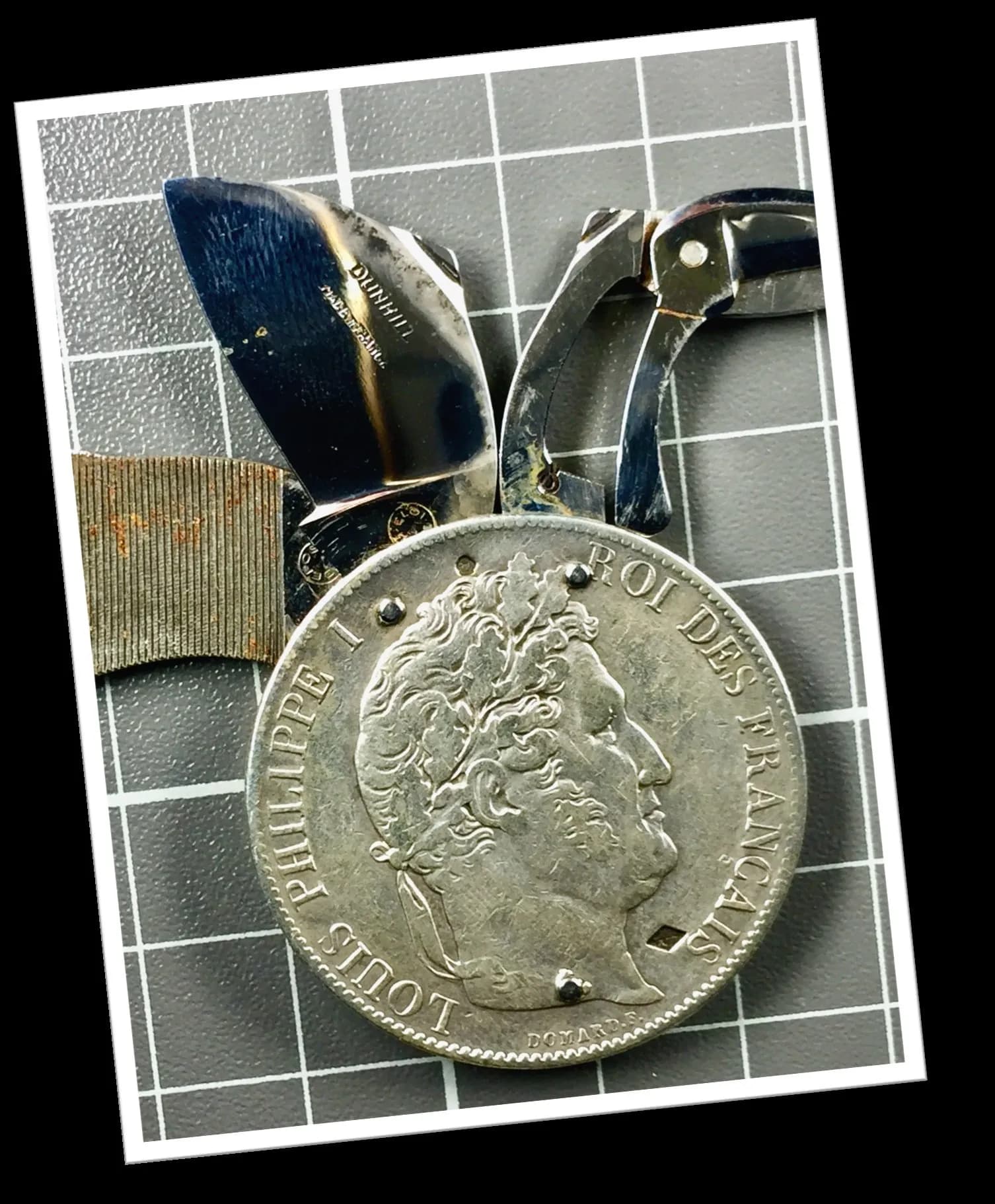 Onglier Dunhill Eloi 1970 en argent avec écu Louis Philippe I 1845, manche noir gravé et lame pliante sur fond carrelé